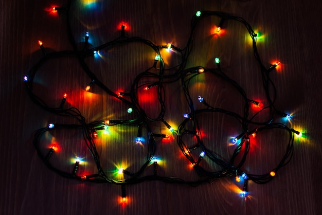 Ghirlanda di Natale su uno sfondo di legno. Brillante mazzo multicolore di luci natalizie.