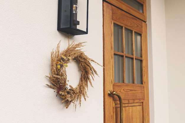 Ghirlanda rustica d'autunno appesa alla parete all'ingresso della casa Decorazione autunnale elegante dell'ingresso o del portico della fattoria Disposizione autunnale