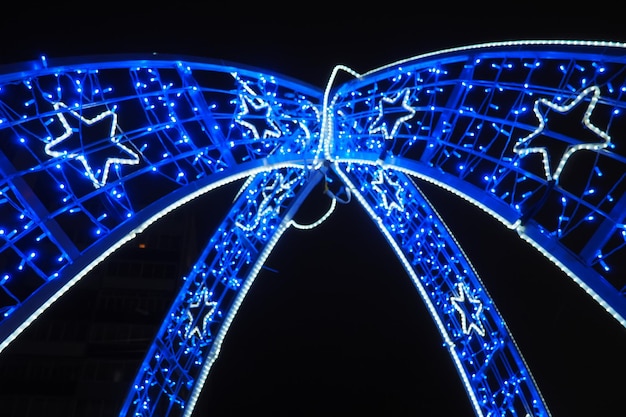 Ghirlande di strada blu Bokeh sfocato Sfondo festivo Lampadine blu e bianche come decorazione per il nuovo anno e la notte di Natale Design della decorazione della strada Punti luminosi astratti Forma a stella