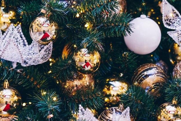 Ghirlande e decorazioni dorate delle sfere di Natale sul primo piano dell'albero di nuovo anno