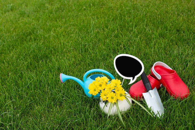 Giardinaggio. lavorare in giardino. strumenti, annaffiatoio e fiore in una pentola su uno sfondo di foglie verdi. Copia spazio. Fondo in legno scuro.