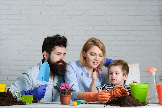 Giardinaggio mamma papà e figlio che piantano fiori a casa famiglia per piantare fiori in vaso bambino con i genitori