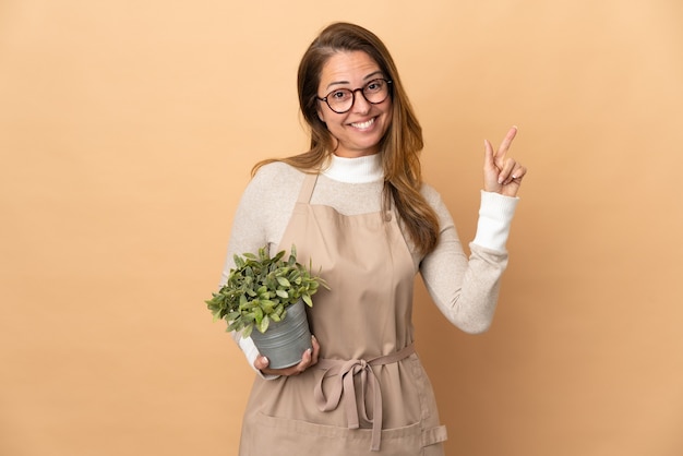 Giardiniere di mezza età donna che tiene una pianta isolata