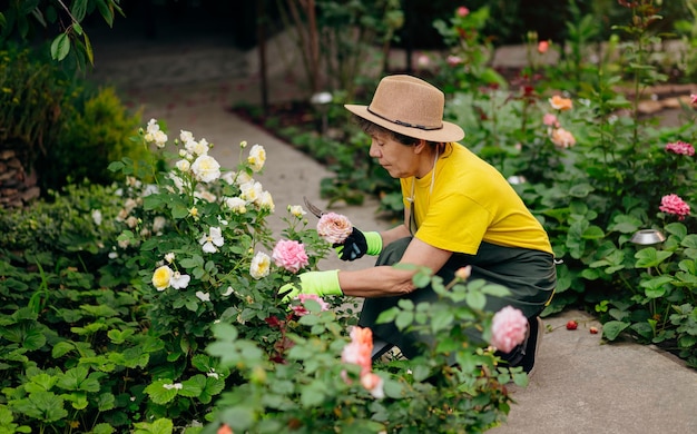 Giardiniere donna senior in un cappello che lavora nel suo cortile con strumenti di lavoro Il concetto di giardinaggio che cresce e si prende cura di fiori e piante