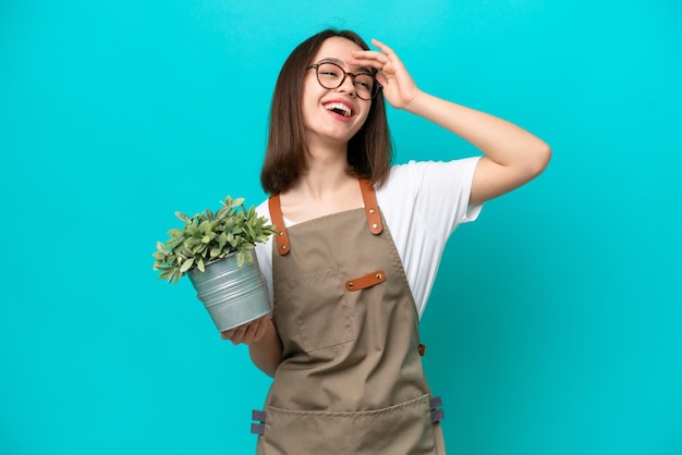 Giardiniere Donna ucraina in possesso di una pianta isolata su sfondo blu sorridente molto