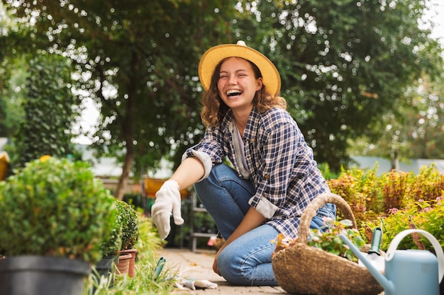 Giardiniere femminile con acqua può lavorare vicino a fiori in serra