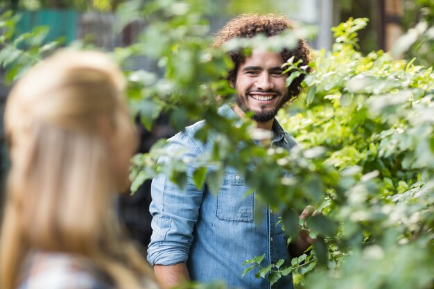 Giardiniere maschio che esamina le piante facenti una pausa della donna