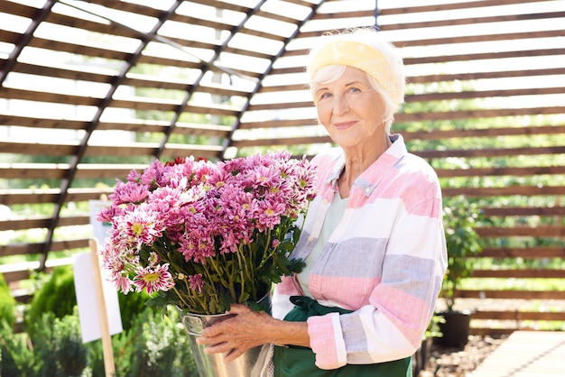 Giardiniere senior che posa con i fiori