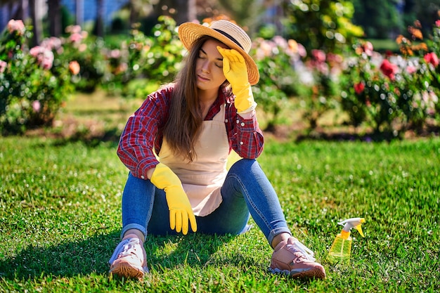 Giardiniere stanco della donna che si siede nell'erba