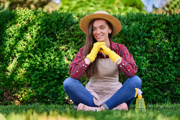 Giardiniere stanco della donna che si siede nell'erba