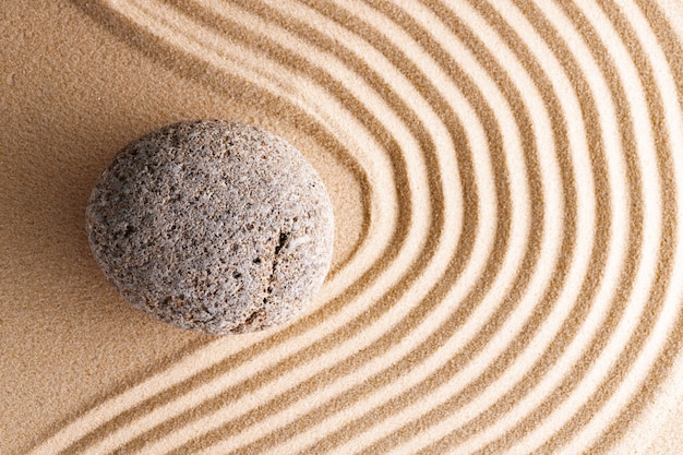 Giardino zen giapponese con pietra nella sabbia rastrellata