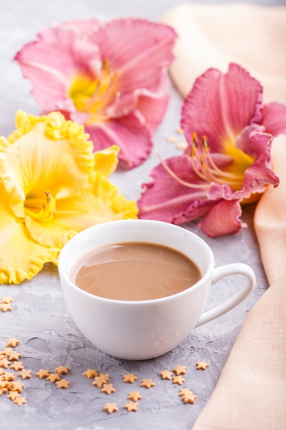 Gigli di giorno gialli e viola con la tazza di caffè