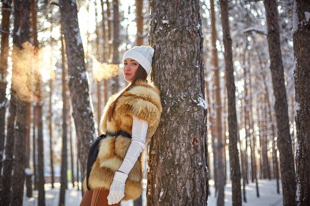 Gilet di pelliccia su una bellissima giovane donna caucasica in una foresta di sole invernale