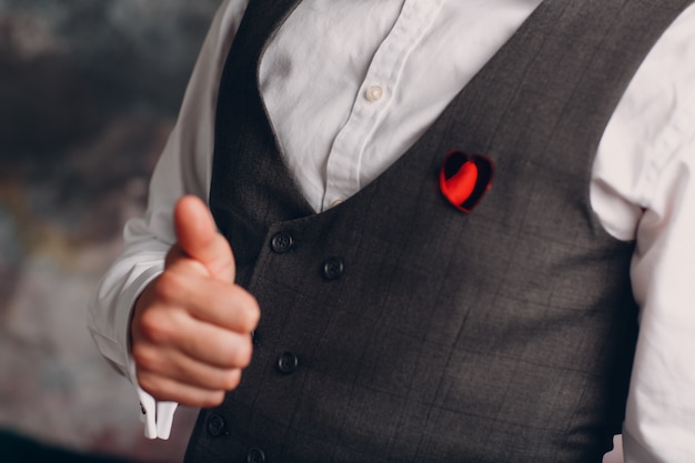 gilet uomo d'affari con spilla a cuore e pollice in su. Concetto di business e successo.