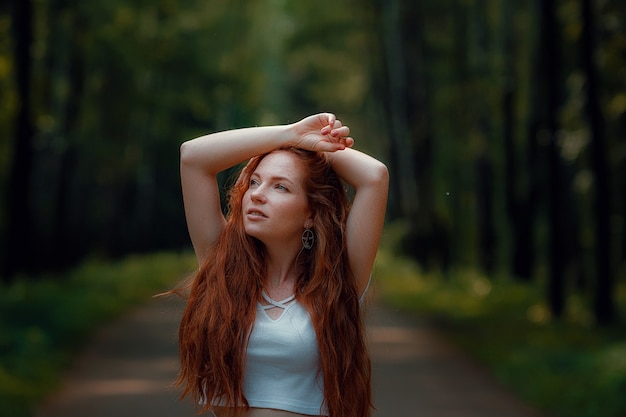 Ginger giovane bella donna in posa in una foresta verde