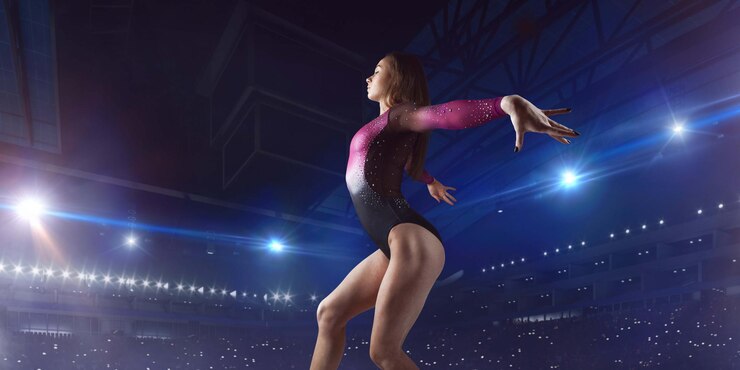 Ginnasta che fa un trucco complicato sulla trave di bilanciamento della ginnastica in un'arena professionale