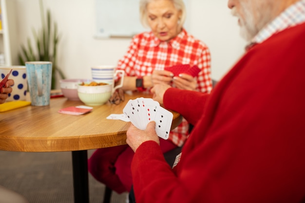 Giocare a carte. Diverse carte sono nelle mani di un simpatico uomo anziano simpatico