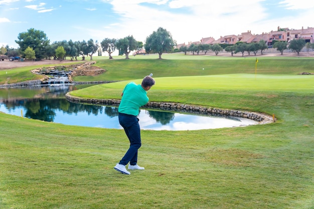 Giocare a golf in una mazza da golf in riva al lago, colpire la pallina con il ferro o lanciare