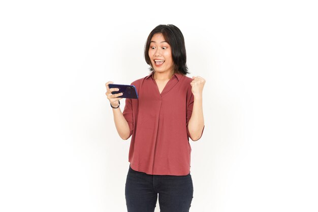 Giocare al gioco per cellulare sullo smartphone di una bella donna asiatica isolata su sfondo bianco
