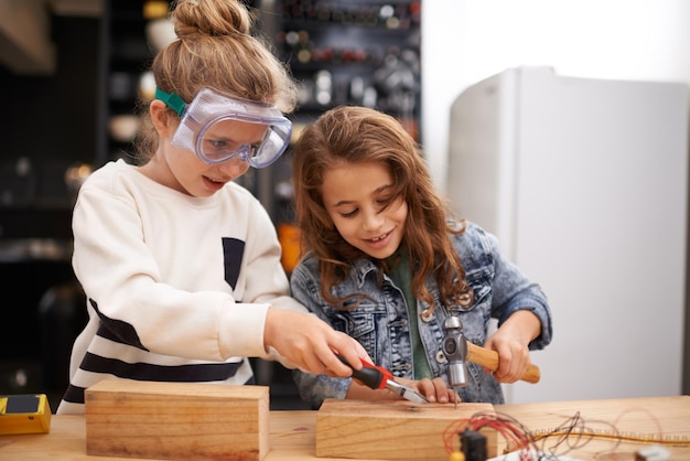 Giocare con gli strumenti di papà è lo scatto migliore di due bambine impegnate al lavoro per creare qualcosa con gli strumenti