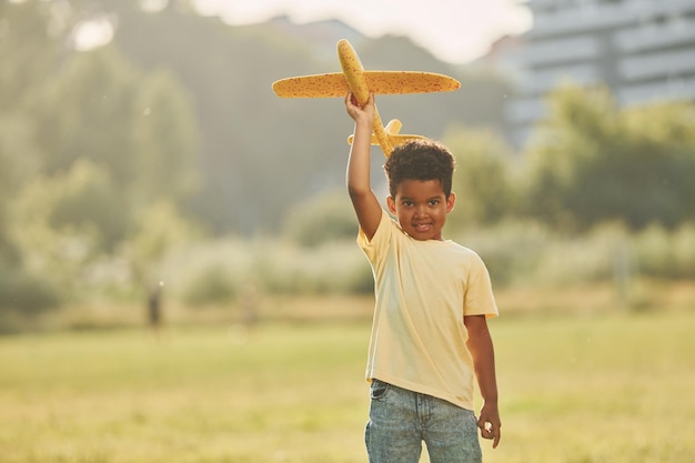 Giocare con l'aereo Il bambino afroamericano si diverte sul campo durante il giorno d'estate