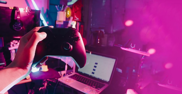 Giocatore che gioca al gioco online con controller joystick in neon bagliore scuro cyberpunk giochi in camera e tornei di sfida di eSport streamer streaming con dispositivo analogico in soggiorno
