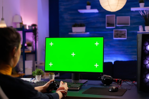 Giocatore competitivo che cerca un potente PC con schermo verde che gioca a giochi online per tornei dal vivo. Giocatore informatico che utilizza PC con giochi sparatutto in streaming desktop isolati con simulazione di crominanza