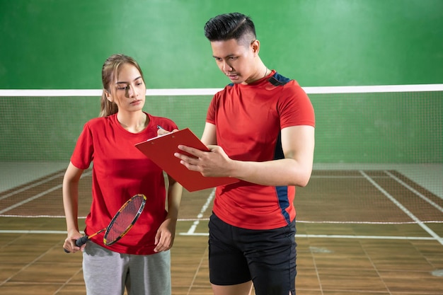 Giocatore di badminton femminile che presta attenzione alle istruzioni degli allenatori con gli appunti