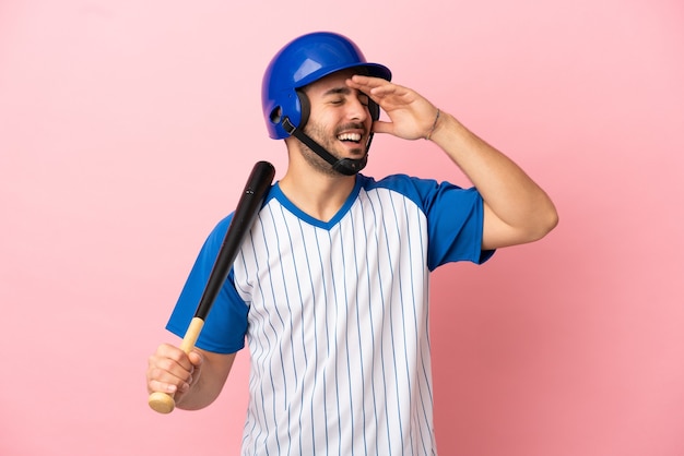 Giocatore di baseball con casco e mazza isolato su sfondo rosa che sorride molto