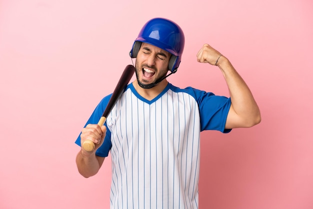 Giocatore di baseball con casco e pipistrello isolato su sfondo rosa che fa un gesto forte