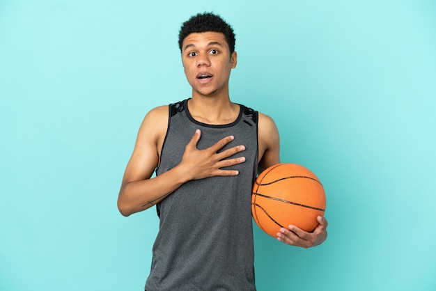 Giocatore di basket afroamericano isolato su sfondo blu sorpreso e scioccato mentre guarda a destra