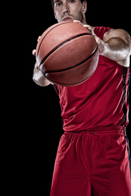 Giocatore di basket con una palla in mano e una divisa rossa. studio fotografico.