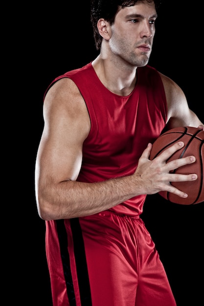 Giocatore di basket con una palla in mano e una divisa rossa. studio fotografico.