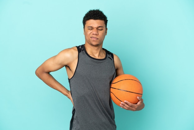 Giocatore di basket uomo afroamericano isolato su sfondo blu che soffre di mal di schiena per aver fatto uno sforzo