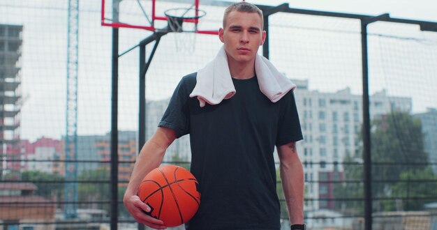 Giocatore di basket uomo con palla sul terreno di gioco guardando la fotocamera Stile di vita sano e concetto di sport