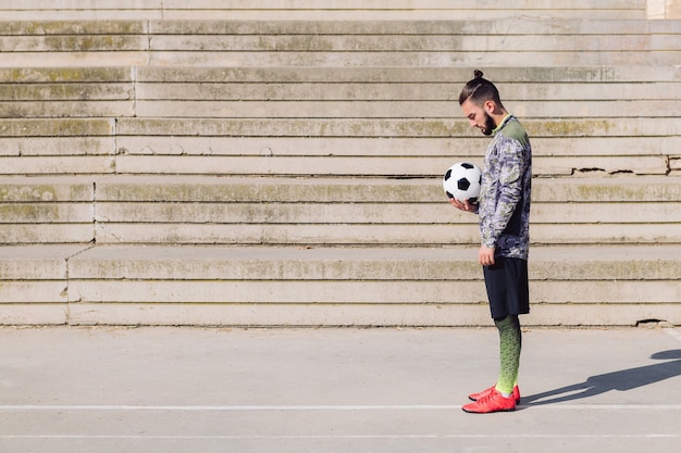 Giocatore di calcio in piedi con la palla in mano