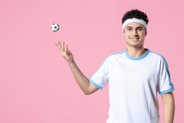 Giocatore di calcio sorridente di vista frontale in vestiti di sport con pallina