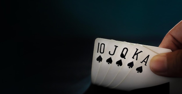 Giocatore di carte da gioco Royal State Flush che apre un primo piano di carte da poker e un tono scuro