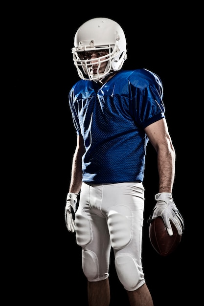 Giocatore di football americano con il numero su un'uniforme blu e una palla in mano.