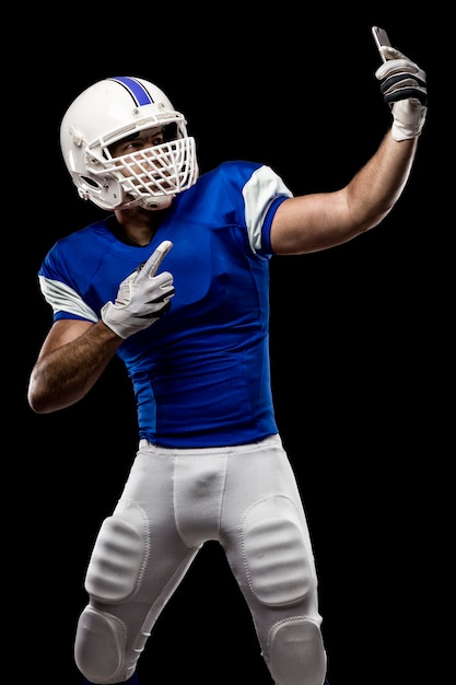 Giocatore di football americano con un'uniforme blu che fa un selfie su una parete nera