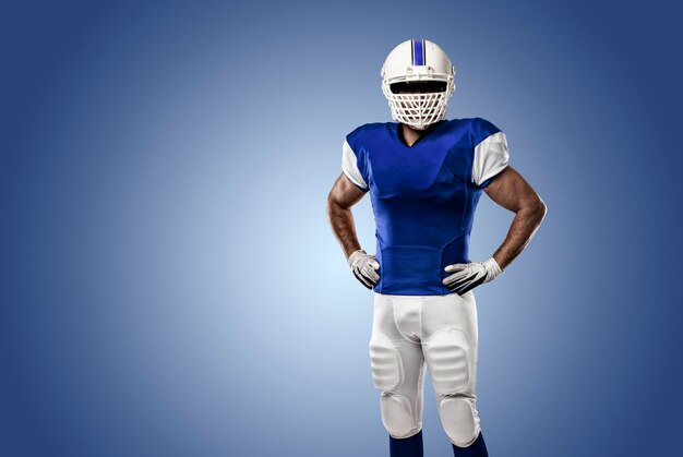 Giocatore di football americano con un'uniforme blu su una parete blu