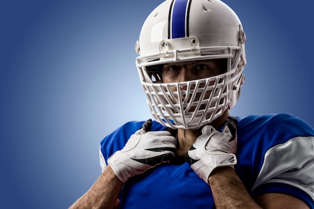 Giocatore di football americano con un'uniforme blu su una parete blu