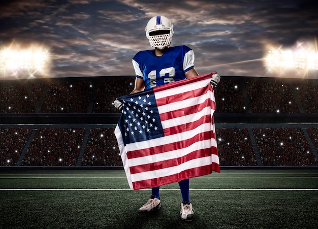 Giocatore di football americano con una divisa blu e una bandiera americana, su uno stadio