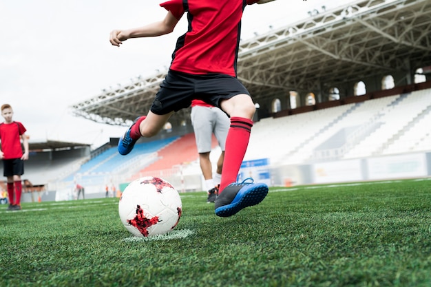 Giocatore di football americano irriconoscibile che dà dei calci alla palla