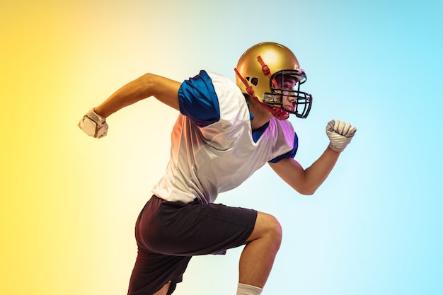 Giocatore di football americano isolato sulla superficie dello studio gradiente in luce al neon