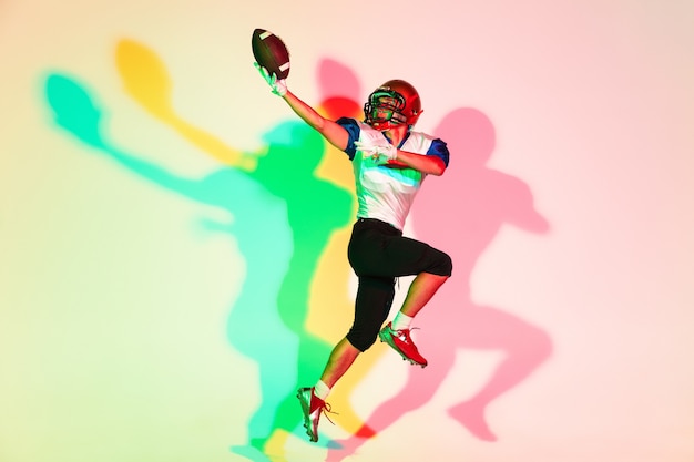 Giocatore di football americano su sfondo sfumato studio in neon