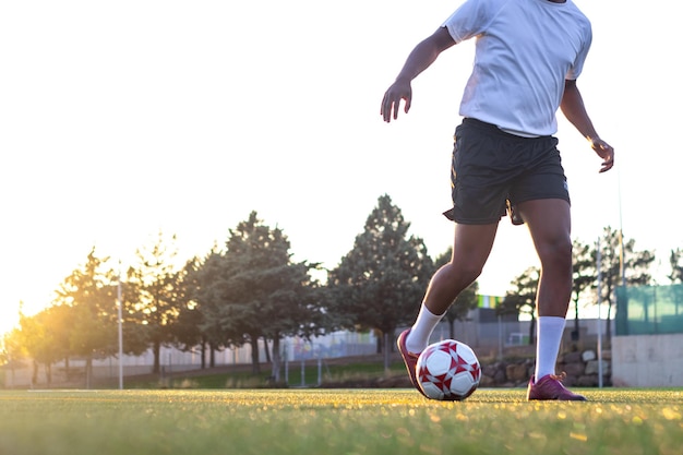 Giocatore di football sul campo che corre con la palla Primo piano dei piedi del giocatore che corre con la palla sul campo Piedi del giocatore con la palla che segna un gol