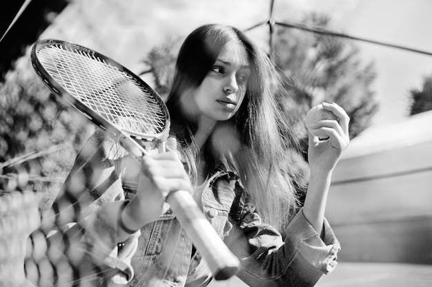 Giocatore di giovane ragazza sportiva con racchetta da tennis sul campo da tennis