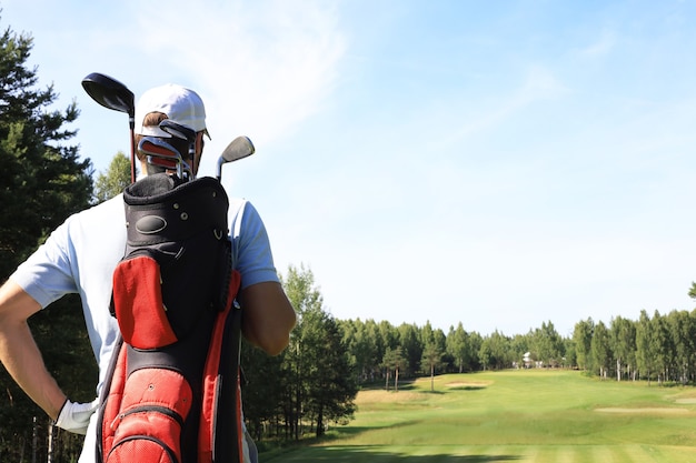 Giocatore di golf che cammina e porta la borsa sul campo durante il gioco estivo del golf.