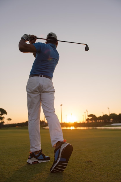giocatore di golf che colpisce campo lungo con autista in corso al bel tramonto